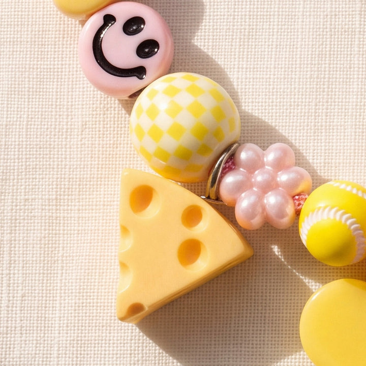 BEADBOO Swiss Cheese charm hanging on a handmade beaded dog collar [crop:charm-cheese__iris]