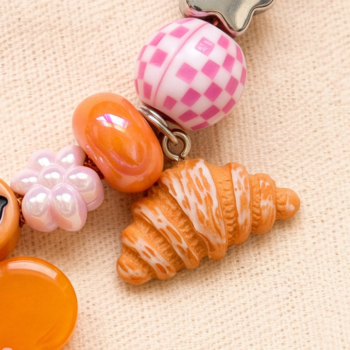 BEADBOO Butter Croissant charm hanging on a handmade beaded dog collar [crop:charm-croissant-baked__honey]
