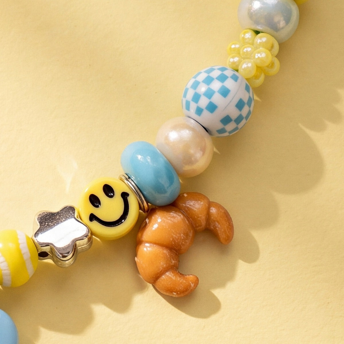 BEADBOO Glazed Croissant charm hanging on a handmade beaded dog collar [crop:charm-croissant__dollar]