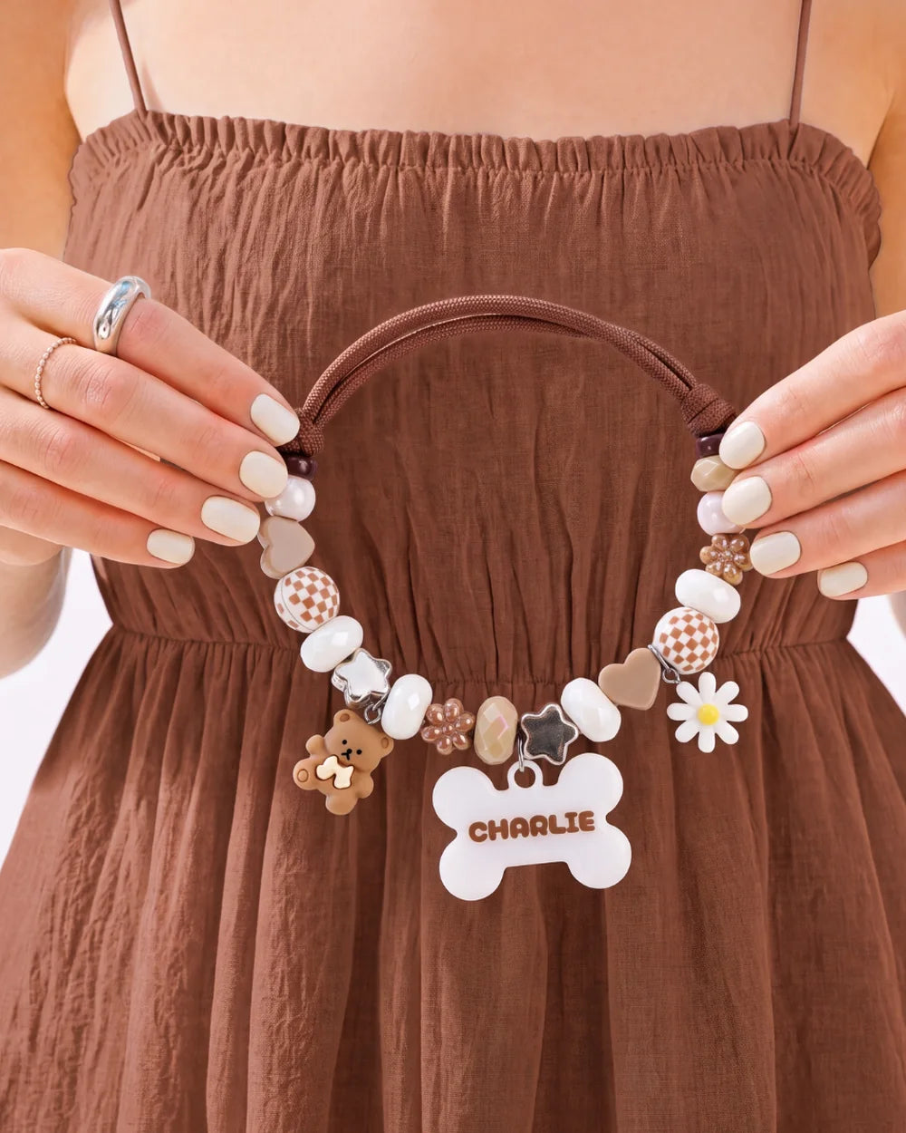 Hands holding up a BEADBOO beaded collar with a white bone tag that says Charlie